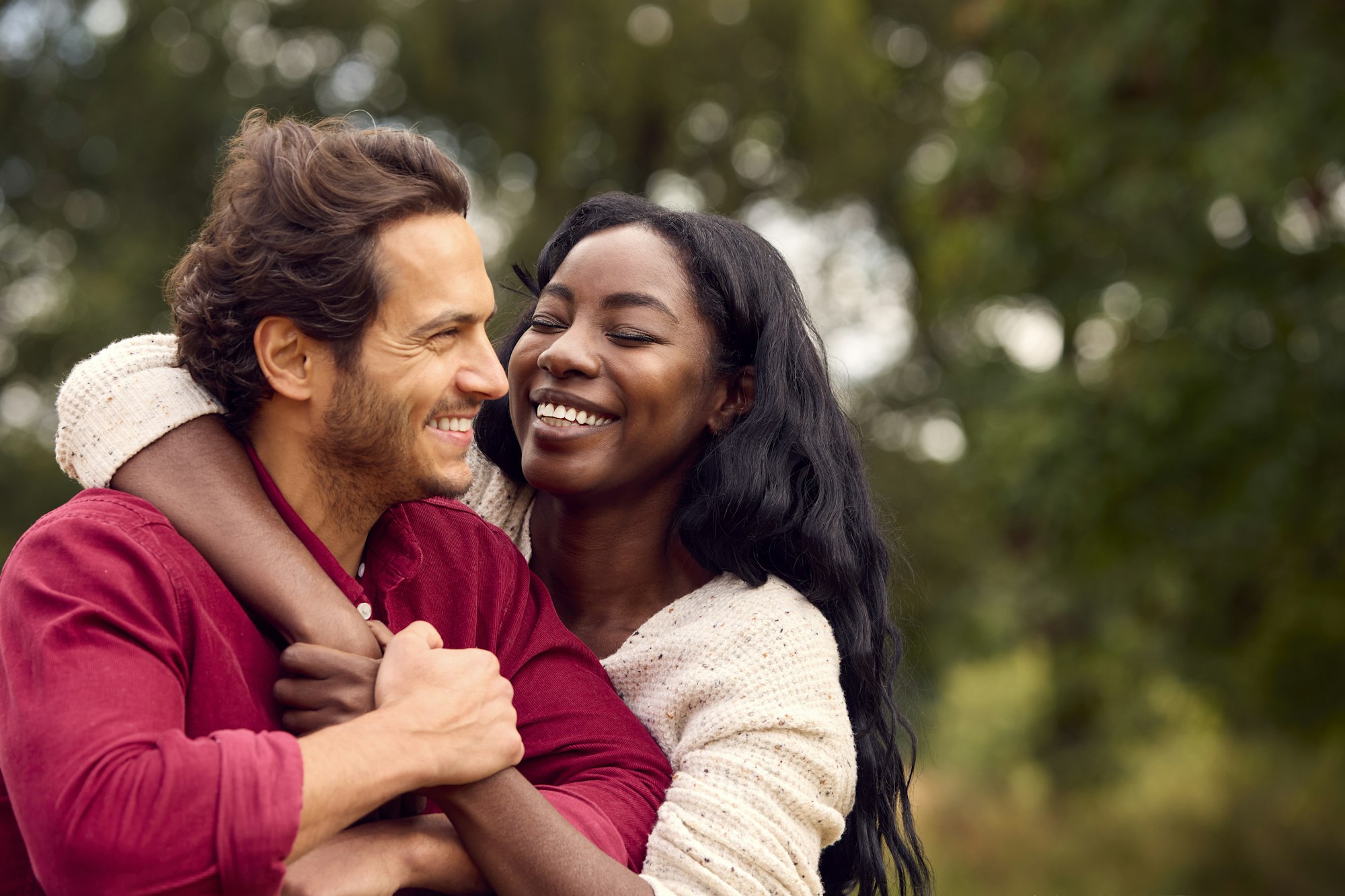 Loving Mixed Race Couple Leaning On Fence On Walk In Countryside