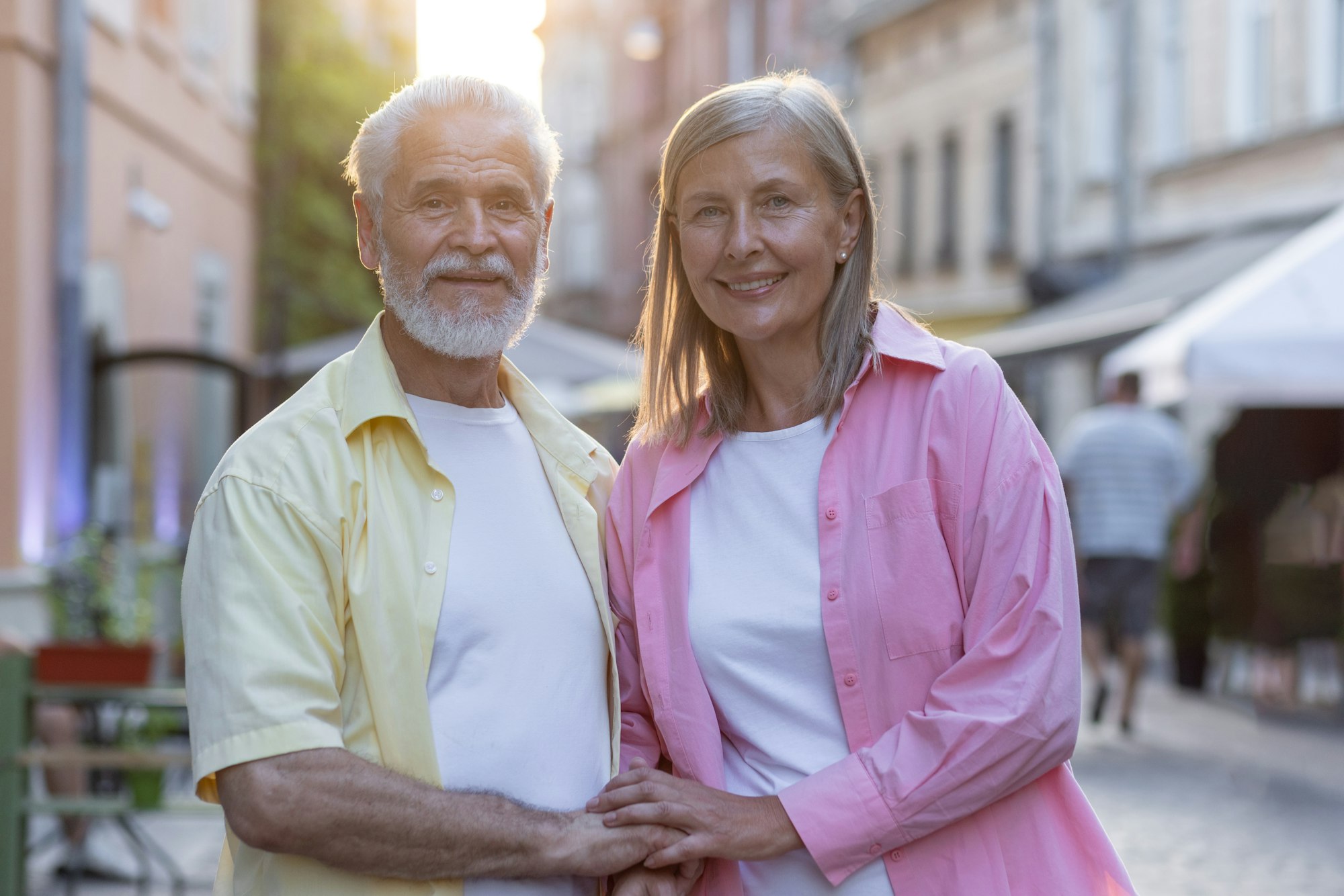 Portrait of an older couple, a man and a woman standing together on a city street, hugging and